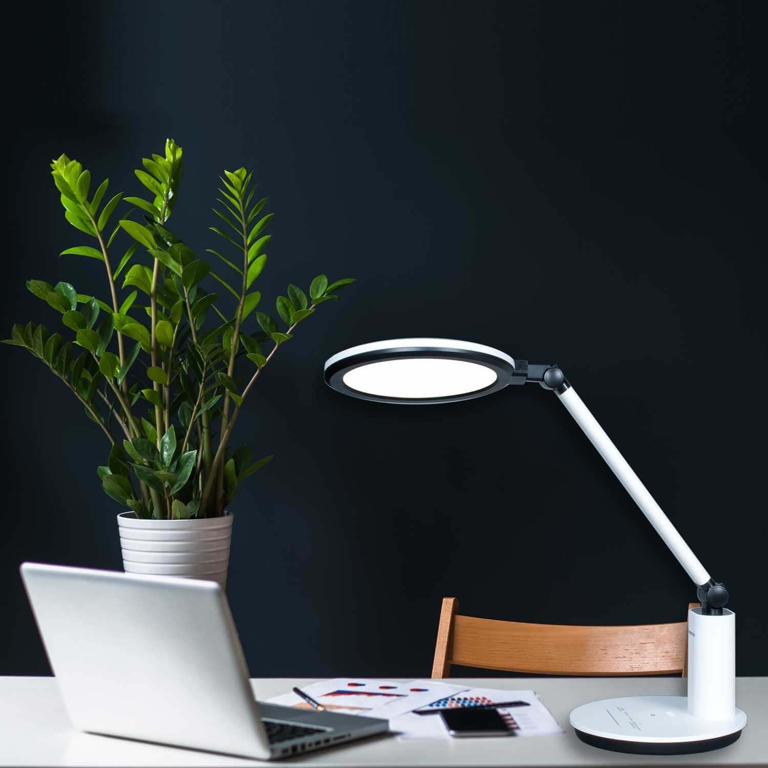 Lampada da tavolo LED Lumeno che illumina una scrivania con un portatile la sera